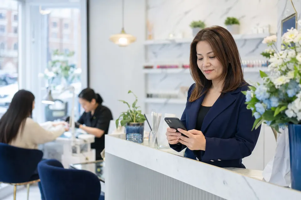 Salon owner checking her phone inside a busy nail salon